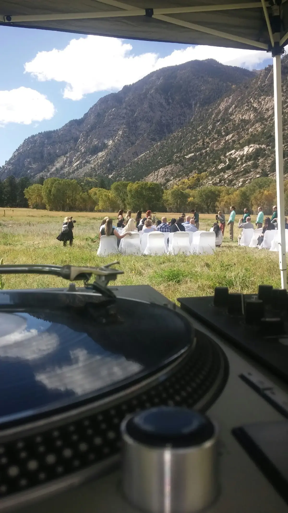 View from DJ booth of outdoor mountain wedding ceremony in Colorado with dramatic mountain backdrop